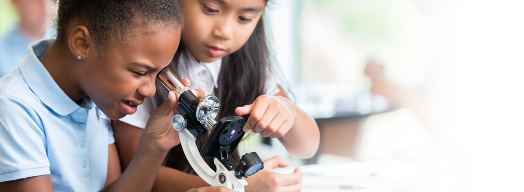 Focused schoolgirls help one another with their assignment in science class at their elementary school.